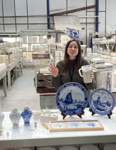 Woman explaining delft plates and pottery in factory in Holland